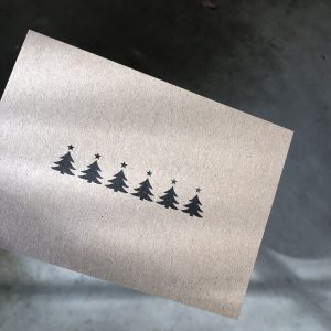 weihnachtskarte mit ausgeschnittenen tannen und sterne