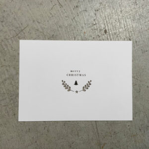postkarte mit gedruckter tanne und ausgeschnittenen zweigen graukarton